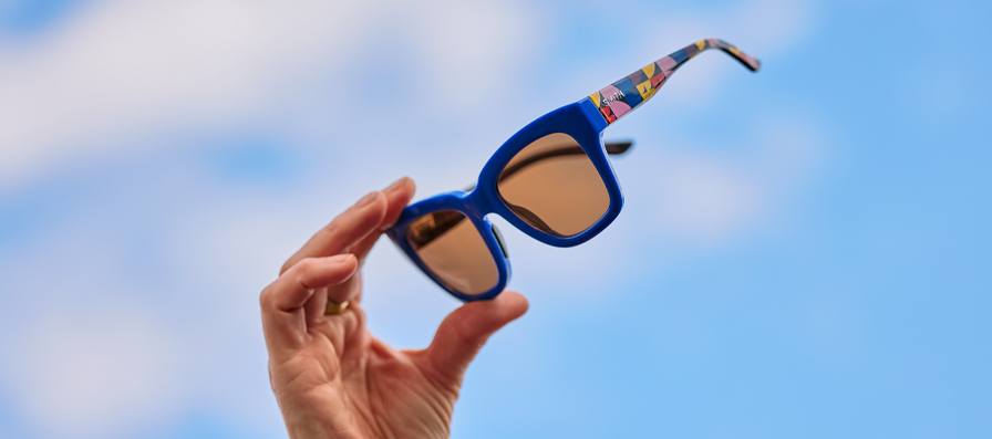 Hand holding Smith x Lisa Congdon limited edition Sway Rx sunglasses up to the sky